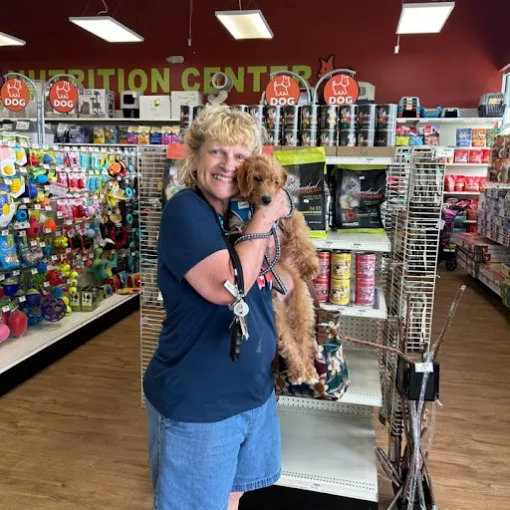 A smiling woman cuddling a curly-coated puppy