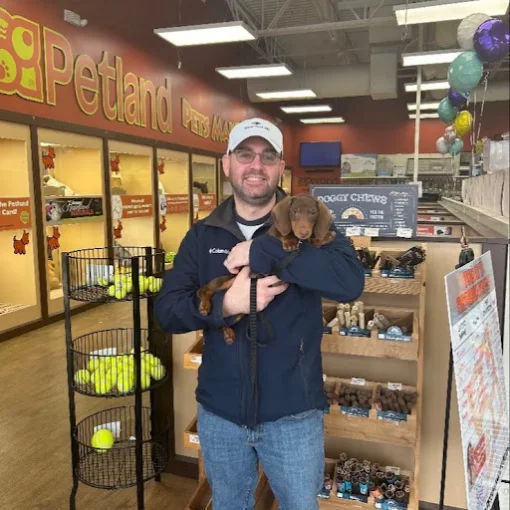 A man holding a brown puppy inside the pet store