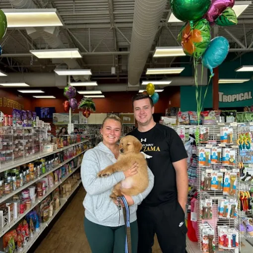 A couple holding a golden puppy inside the pet store